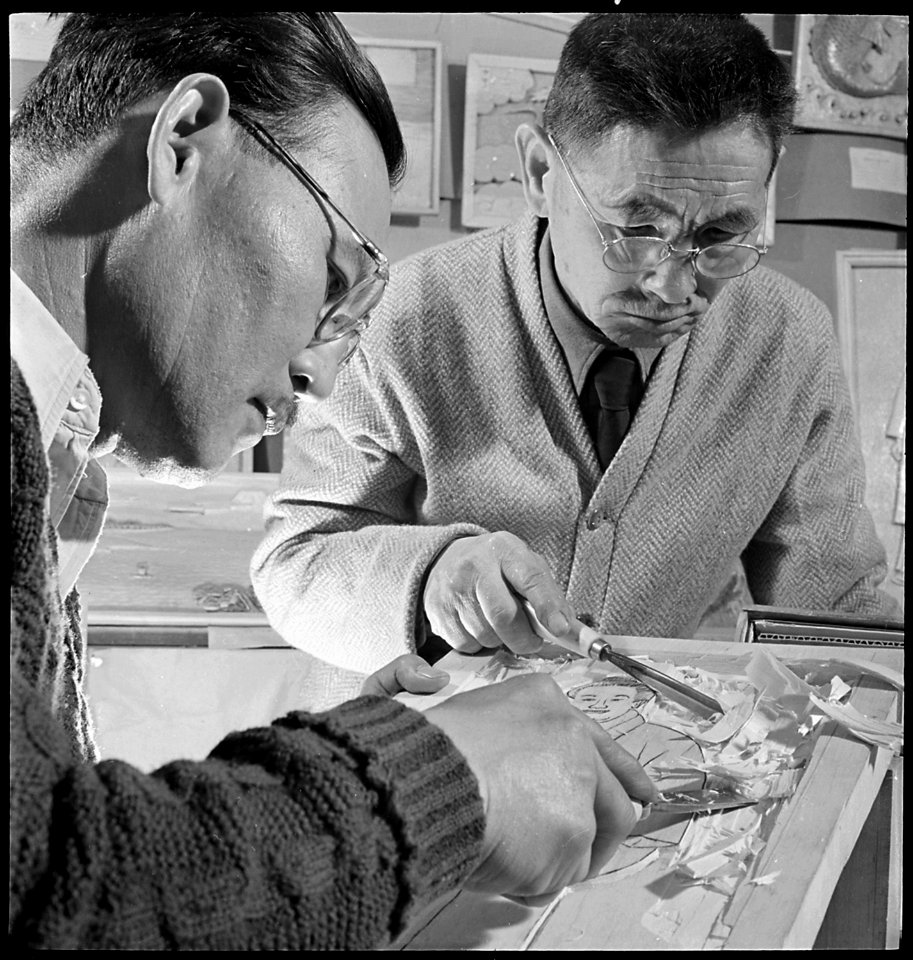 Granada Relocation Center, Amache, Colorado. A woodcarving demonstration by M.Y. Murakami, left, a . . . - NARA - 539302
