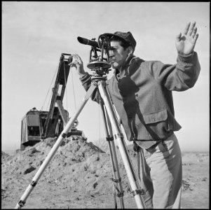 Granada Relocation Center, Amache, Colorado. A young Nisei operates a surveying instrument in layin . . . - NARA - 539125