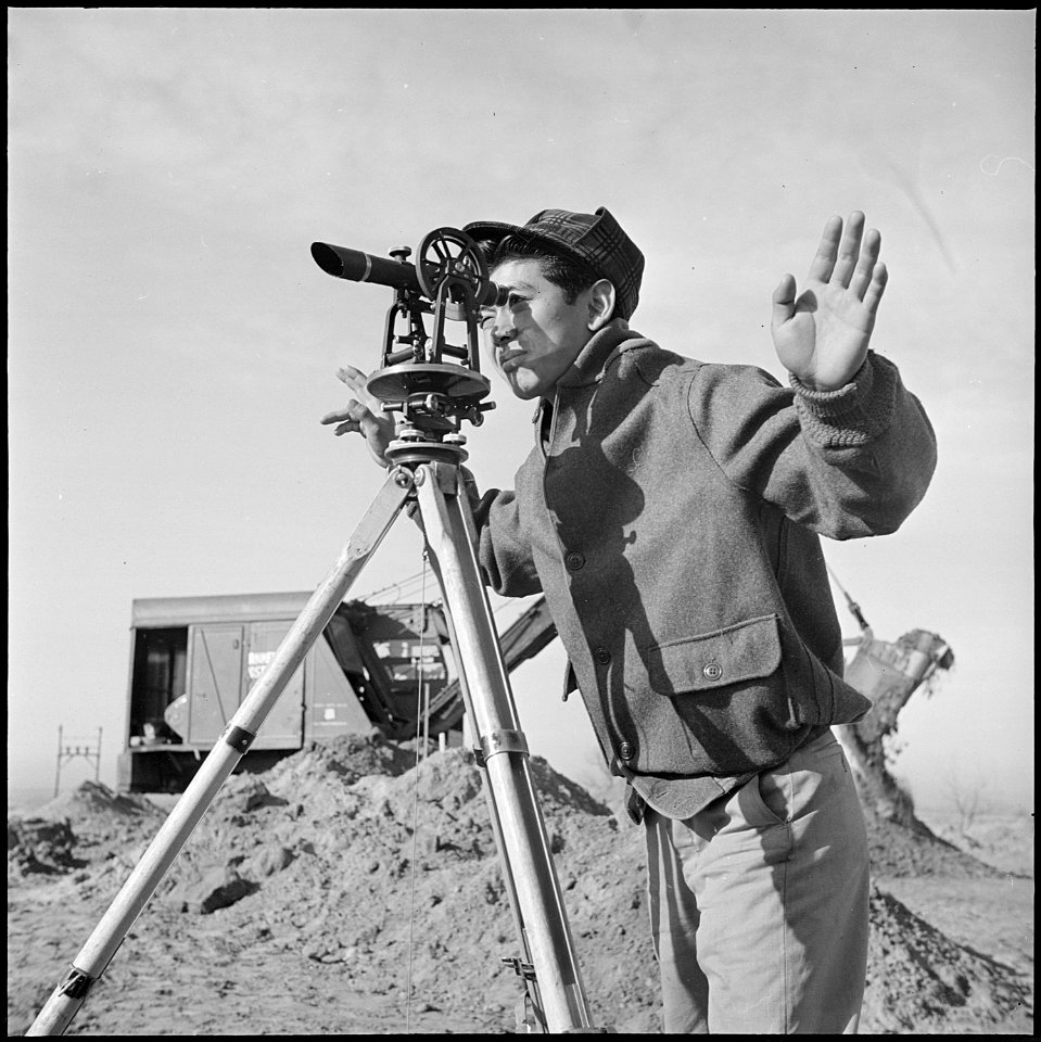 Granada Relocation Center, Amache, Colorado. A young Nisei operates a surveying instrument in layin . . . - NARA - 539126