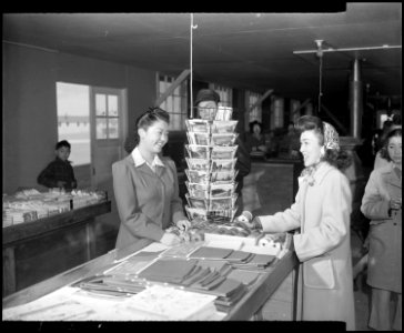 Granada Relocation Center, Amache, Colorado. A young Nisei girl purchases Christmas wrappings in th . . . - NARA - 539016