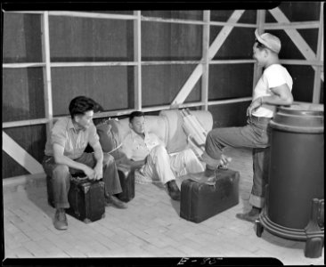 Granada Relocation Center, Amache, Colorado. Three young evacuees drop their baggage and relax to a . . . - NARA - 538748