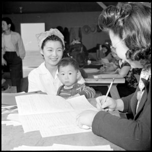 Granada Relocation Center, Amache, Colorado. With her son young Dennis, in her arms, Mrs. T. Sasabu . . . - NARA - 539284