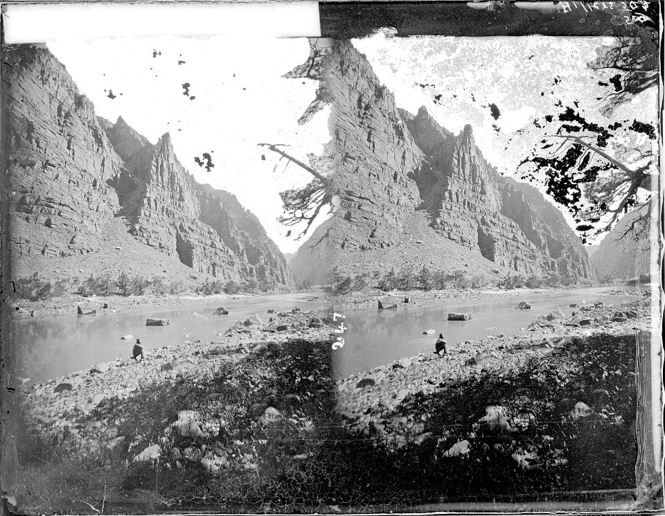 Green River, Lodore Canyon. A hispanic appearing man is seated on a rock at edge of water. Hiller - NARA - 517840