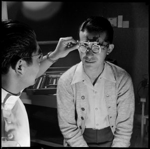 Heart Mountain Relocation Center, Heart Mountain, Wyoming. Optometrist, Wright Kawakami, examines t . . . - NARA - 539458 photo