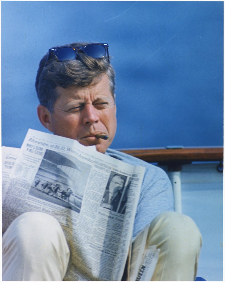Hyannisport Weekend. President Kennedy with cigar and New York Times. Hyannisport, MA, aboard the Honey Fitz. - NARA - 194268