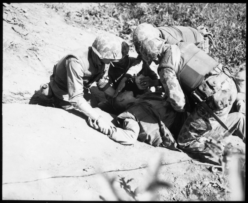 In bitter fighting on Hook Ridge, Marines threw back 800 screaming, bugle-blowing Chinese. A wounded Marine is given... - NARA - 532426