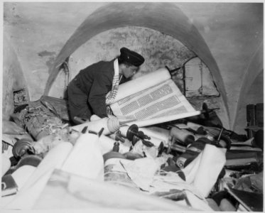 In the cellar of the Race Institute in Frankfurt, Germany, Chaplain Samuel Blinder examines one of hundreds of... - NARA - 531306