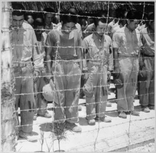 Japanese Prisoners of War at Guam, with bowed heads after hearing Emperor Hirohito make announcement of Japan's... - NARA - 520991