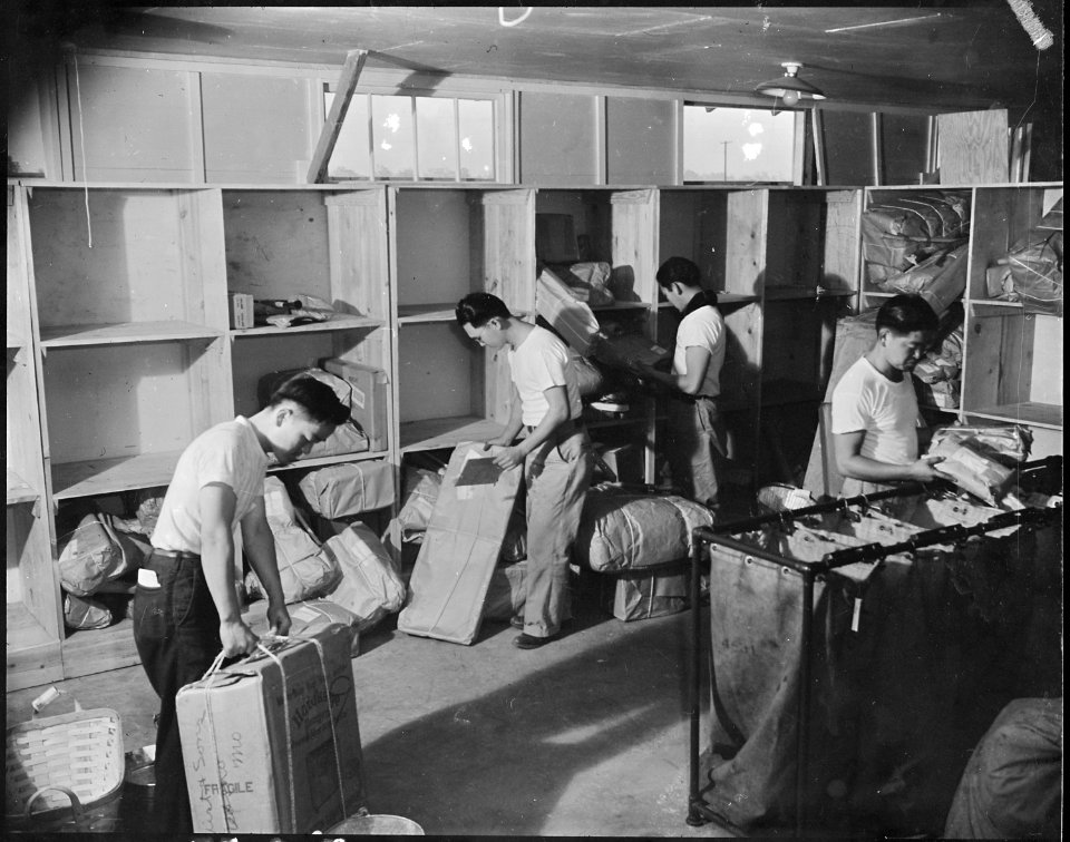 Jerome Relocation Center, Denson, Arkansas. A crew of postal workers engaged in sorting packages at . . . - NARA - 538850