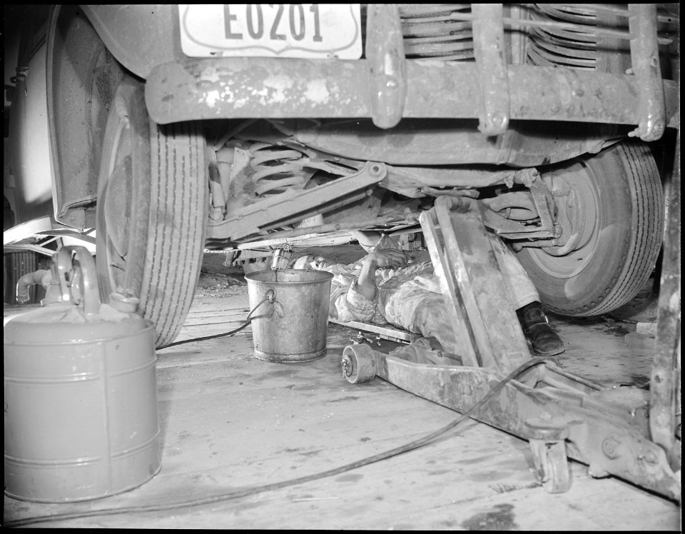 Jerome Relocation Center, Denson, Arkansas. A young Nisei mechanic under a project car in a tempora . . . - NARA - 538993