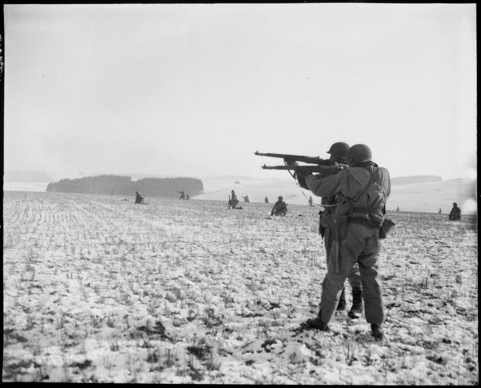 Infantrymen, attached to the 4th Armored Division, fire at German troops, in the American advance to relieve the... - NARA - 531242