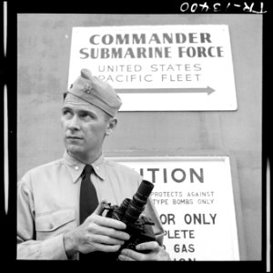 Lcdr. Dwight S. Long, U.S. Navy photographer makes adjustments on his 16mm motion picture camera while on an assignment. - NARA - 520845