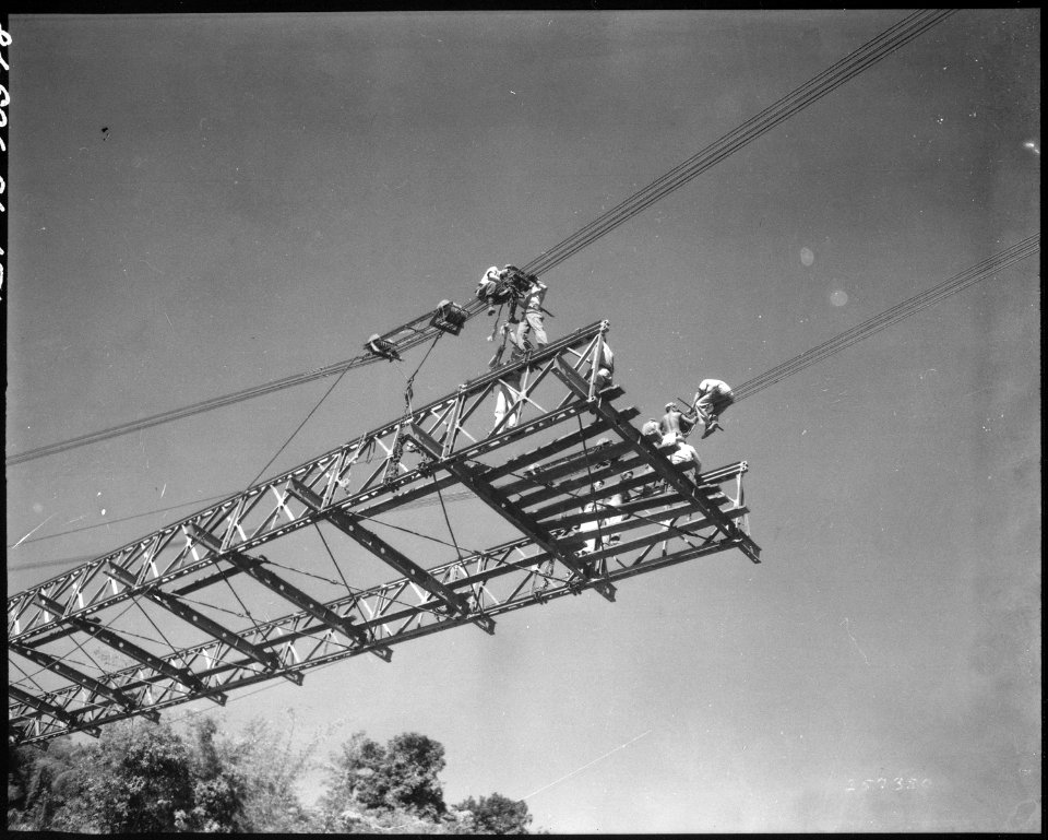 Looking up from Taiping River as cables are attached to suspension clamps of stiffening girder section from west... - NARA - 531339