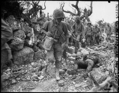 Marines pass through a small village where Japanese soldiers lay dead. Okinawa, April 1945. - NARA - 532552 photo