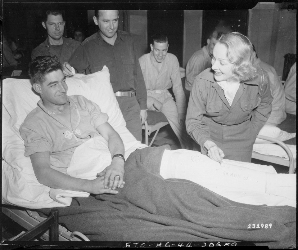 Marlene Dietrich, motion picture actress, autographs the cast on the leg of Tec 4 Earl E. McFarland of Cavider... - NARA - 531330