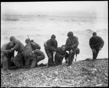 Members of an American landing party lend helping hands to others whose landing craft was sunk by enemy action off... - NARA - 531189