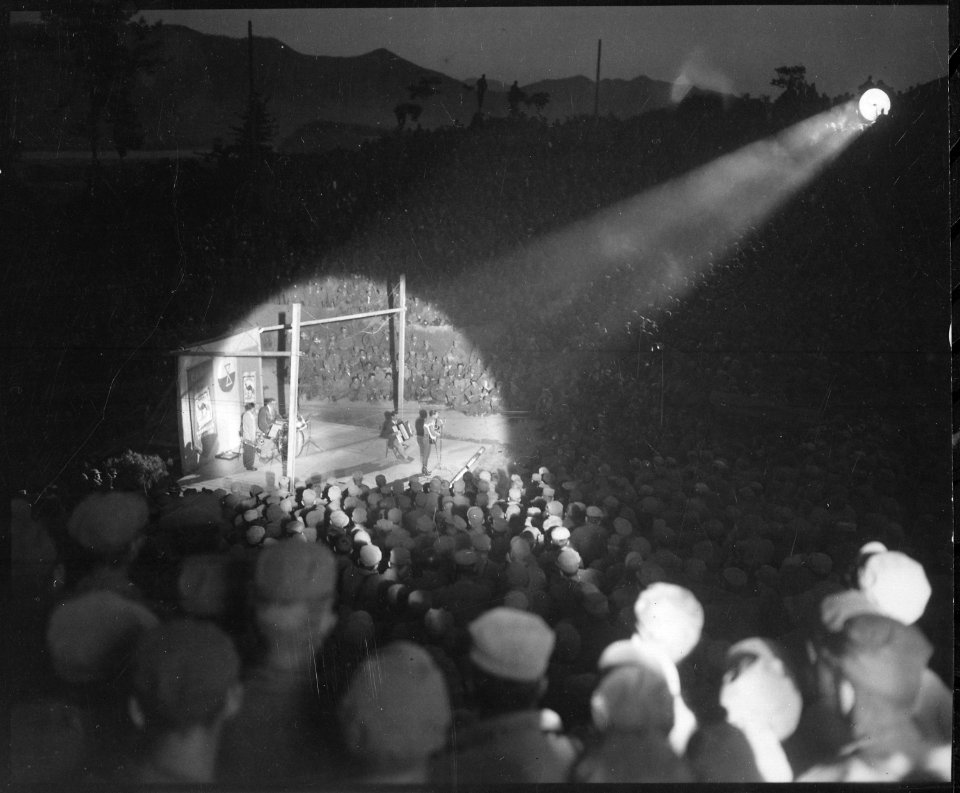 Men of 92nd Engineer Searchlight Company focus on Yodeler Elton Britt during Camel Caravan variety show at Hongchon... - NARA - 531408