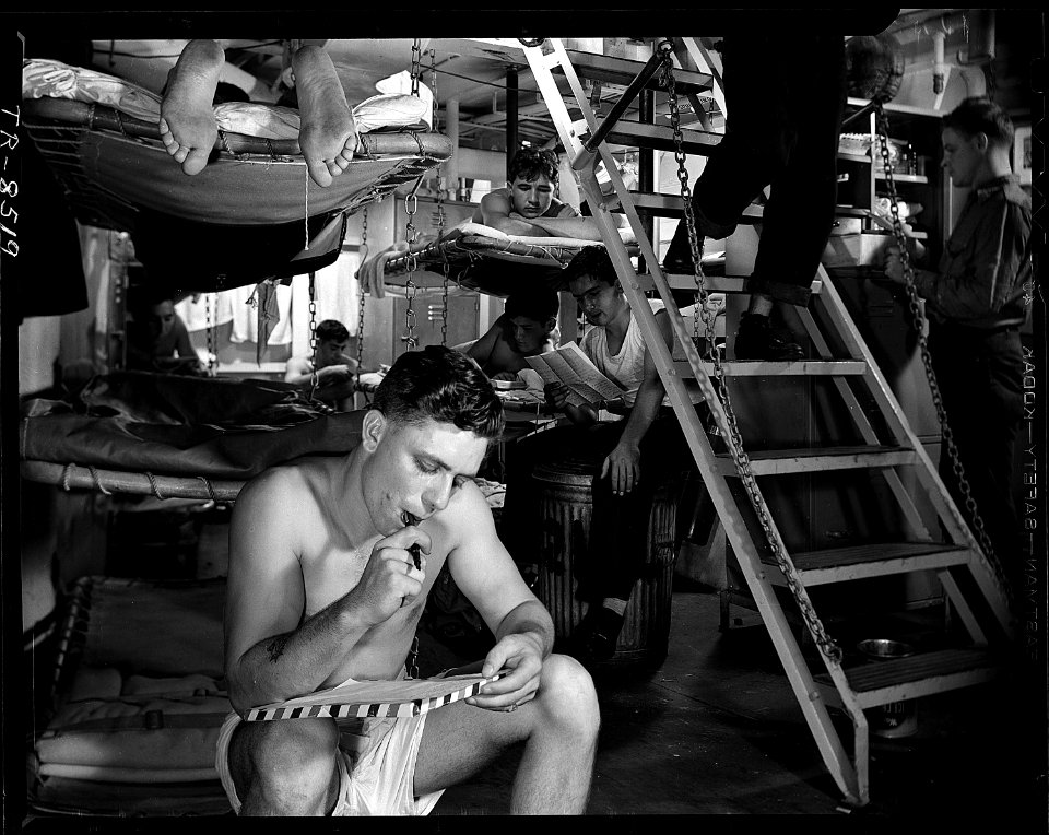 Men read and relax aboard USS Yorktown (CVA-10) in equatorial waters. - NARA - 520756