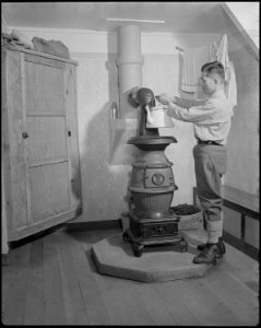 Minidoka Relocation Center, Minidoka, Washington. View in the home of Eizo Nishi. The pot bellied . . . - NARA - 536543
