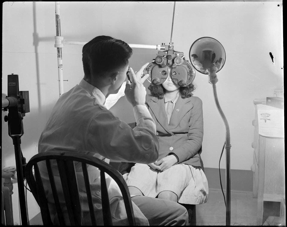 Minidoka Relocation Center. Doctor Geo. Tani. Hospital Series. Doctor examining eyes of girl. - NARA - 536593