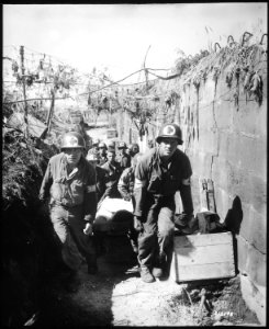 Medics remove a casualty from the battle field to an aid station in an air raid shelter, near Brest, France, formerly... - NARA - 531320 photo