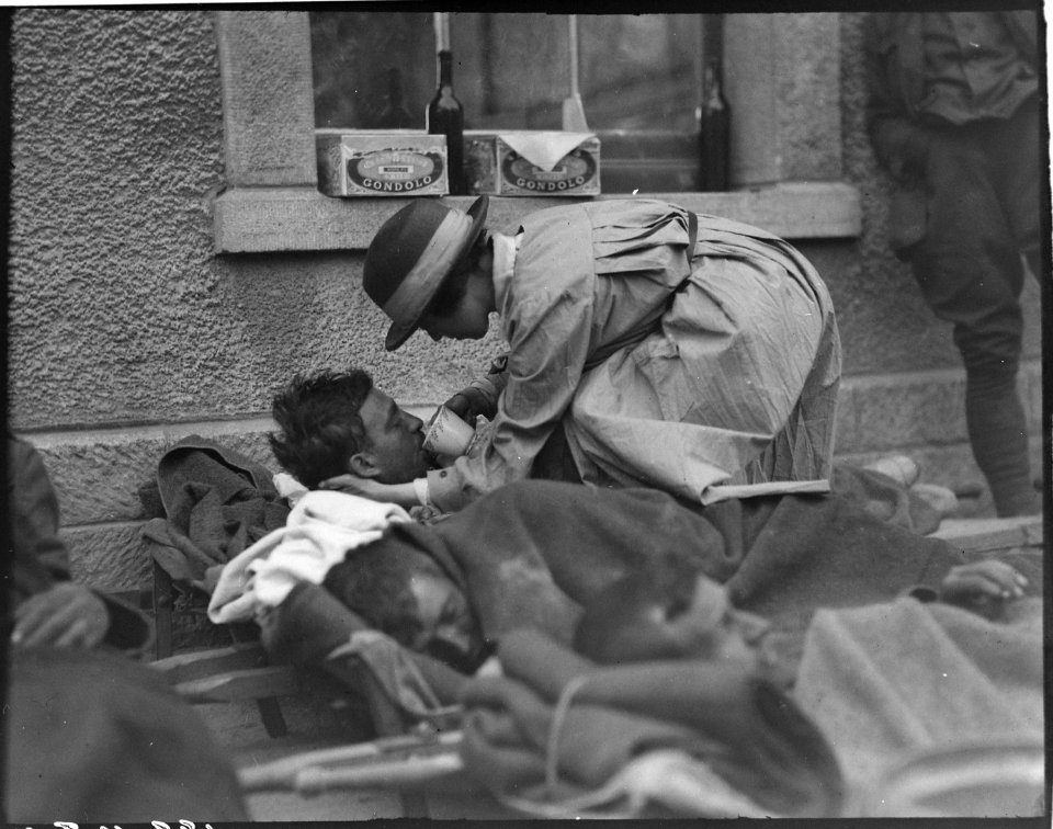 Mrs Hammond, American Red Cross, serving water to badly wounded British soldier on platform of railroad station at... - NARA - 530728