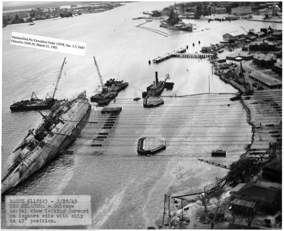 NASPH ^118523- 3-28-43, USS Oklahoma- Salvage, Aerial view looking forward on inshore side with ship in 40 degree... - NARA - 296978