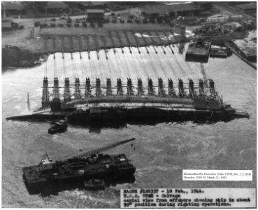 NASPH ^120337- 10 Feb 1944. USS Utah- Salvage, Aerial view from offshore showing ship in about 90 degree position... - NARA - 296983