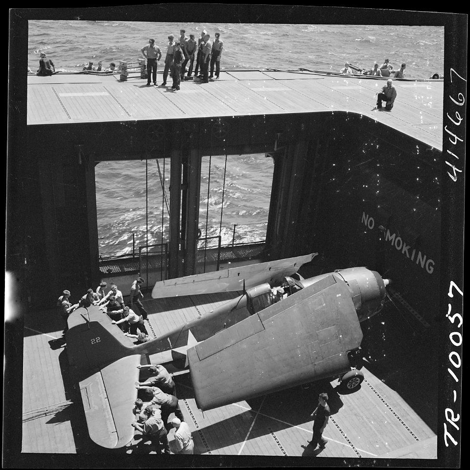 Navy crewmen aboard the USS Monterey (CVL-26) bringing an F6F to the flight deck on elevator. - NARA - 520750