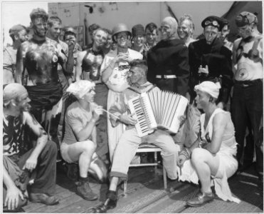 Neptune party on USS ENTERPRISE. Pollywog V. E. Christensen, S2c., gives his shipmates a song or two on the flight deck. - NARA - 520663