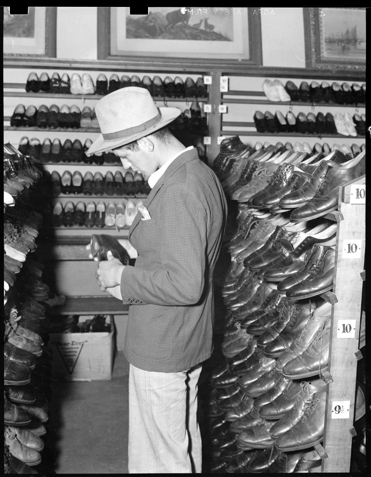 Oakland, California. Youth on Relief. This young agricultural migrant is buying a second hand hat and shoes in the... - NARA - 532144