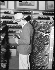 Oakland, California. Youth on Relief. This young agricultural migrant is buying a second hand hat and shoes in the... - NARA - 532144
