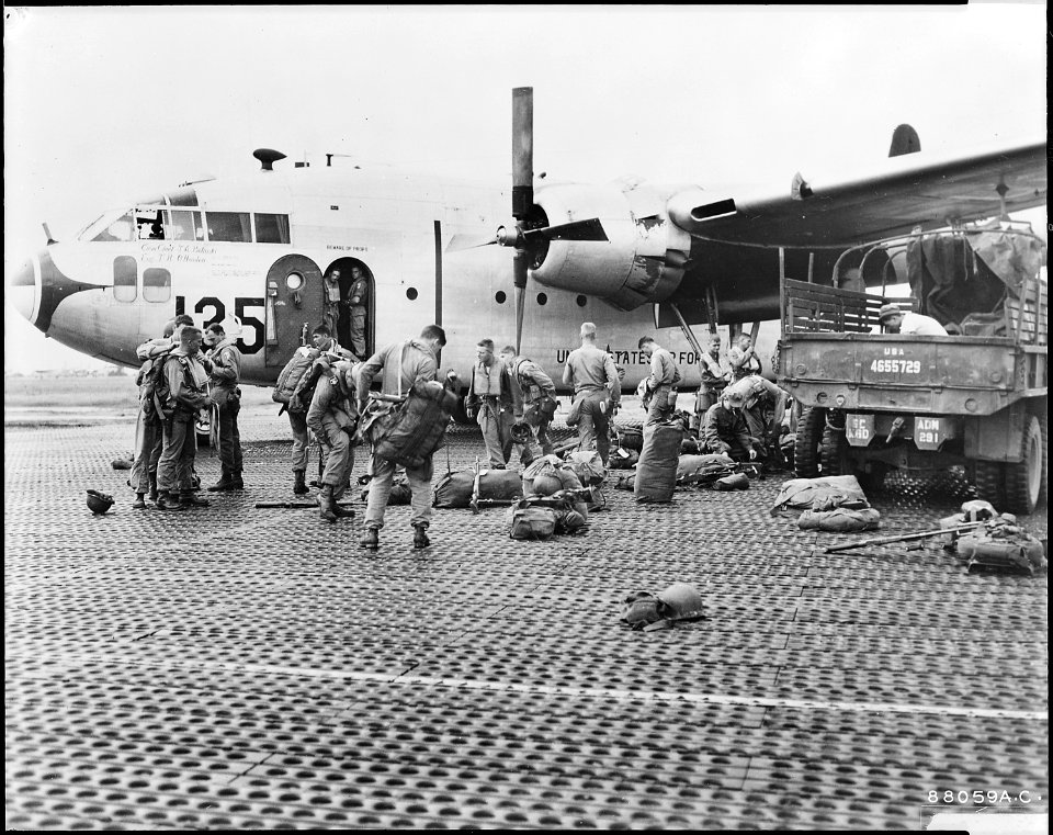 Paratroopers of the 187th Regimental Combat Team put on parachutes and Mae West life preservers before boarding a... - NARA - 542289