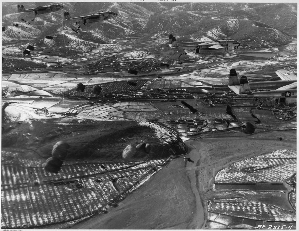 Parachutes billow out behind a formation of 314th Troop Carrier Group C-119 Flying Boxcars over a dropzone in Korea... - NARA - 542364