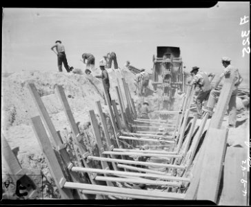 Parker, Arizona. A ditch-digging machine excavates for water pipes and for sewer lines at War Reloc . . . - NARA - 536261 photo