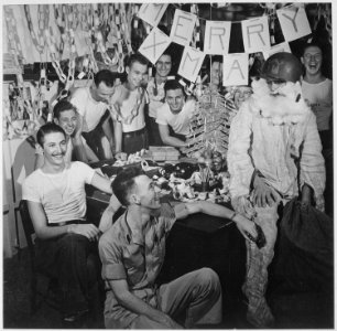 Personnel of USS LEXINGTON celebrate Christmas with make-shift decorations and a firefighting, helmeted Santa Claus. - NARA - 520912