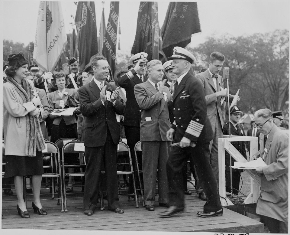 Photograph of Admiral Chester Nimitz arriving on speaker's platform, to the applause of dignitiaries. - NARA - 199212
