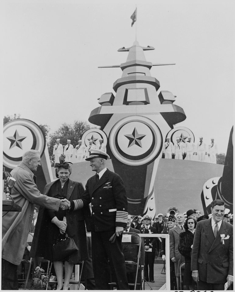 Photograph of Admiral Chester Nimitz on speaker's platform before mock-up of battleship, shaking hands with... - NARA - 199214