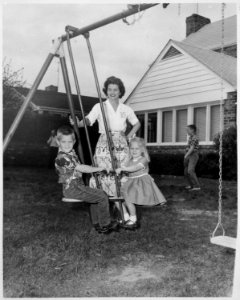 Photograph of Betty Ford Watching as Children Steven Ford and Susan Ford Ride on a Glider in the Backyard of their... - NARA - 186874