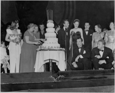 Photograph of First Lady Bess Truman cutting the cake at the Roosevelt Birthday Ball, as Paul Henreid, Alexis Smith... - NARA - 199257 photo