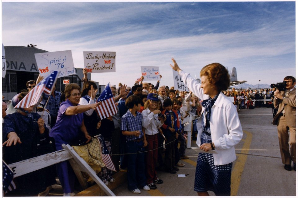 Photograph of First Lady Betty Ford Being Greeted by a Group of Supporters, Many of Which are Carrying Signs, Upon... - NARA - 186826