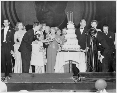 Photograph of First Lady Bess Truman distributing birthday cake to Hollywood celebrities at a Roosevelt Birthday Ball... - NARA - 199338