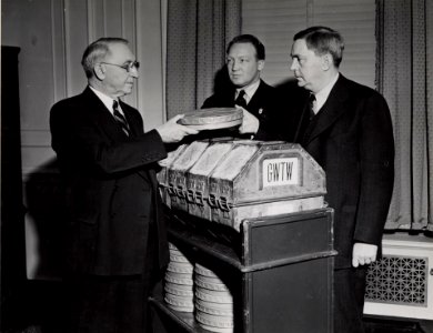 Photograph of First Archivist of the United States R. D. W. Connor Receiving Film Gone With The Wind from Senator George of Georgia and Loew's Eastern Division Manager Carter Barron, 1941