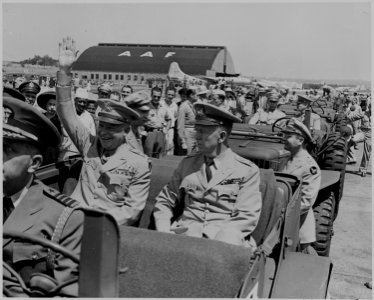 Photograph of General Dwight D. Eisenhower sitting in the back of a jeep with General George C. Marshall, waving to... - NARA - 199108