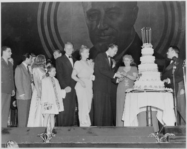 Photograph of First Lady Bess Truman giving actor Cesar Romero a slice of birthday cake during a Roosevelt Birthday... - NARA - 199339