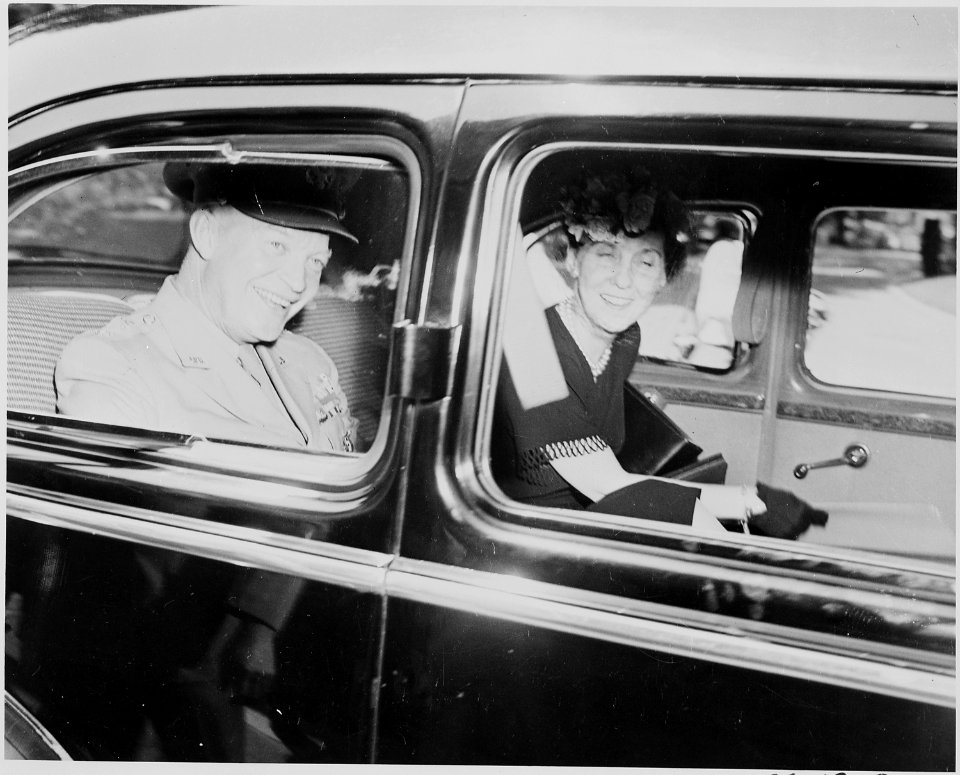 Photograph of General Dwight D. Eisenhower and Mrs. Eisenhower, smiling in the back of a limousine. - NARA - 199122
