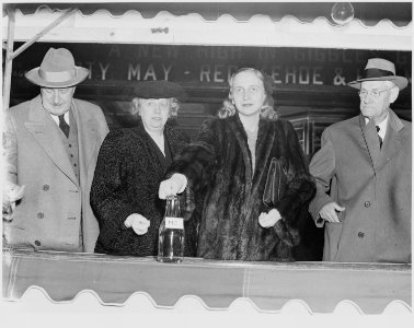 Photograph of Margaret Truman dropping a coin in a bottle marked Mo. as part of a public appearance in behalf of... - NARA - 199307 photo