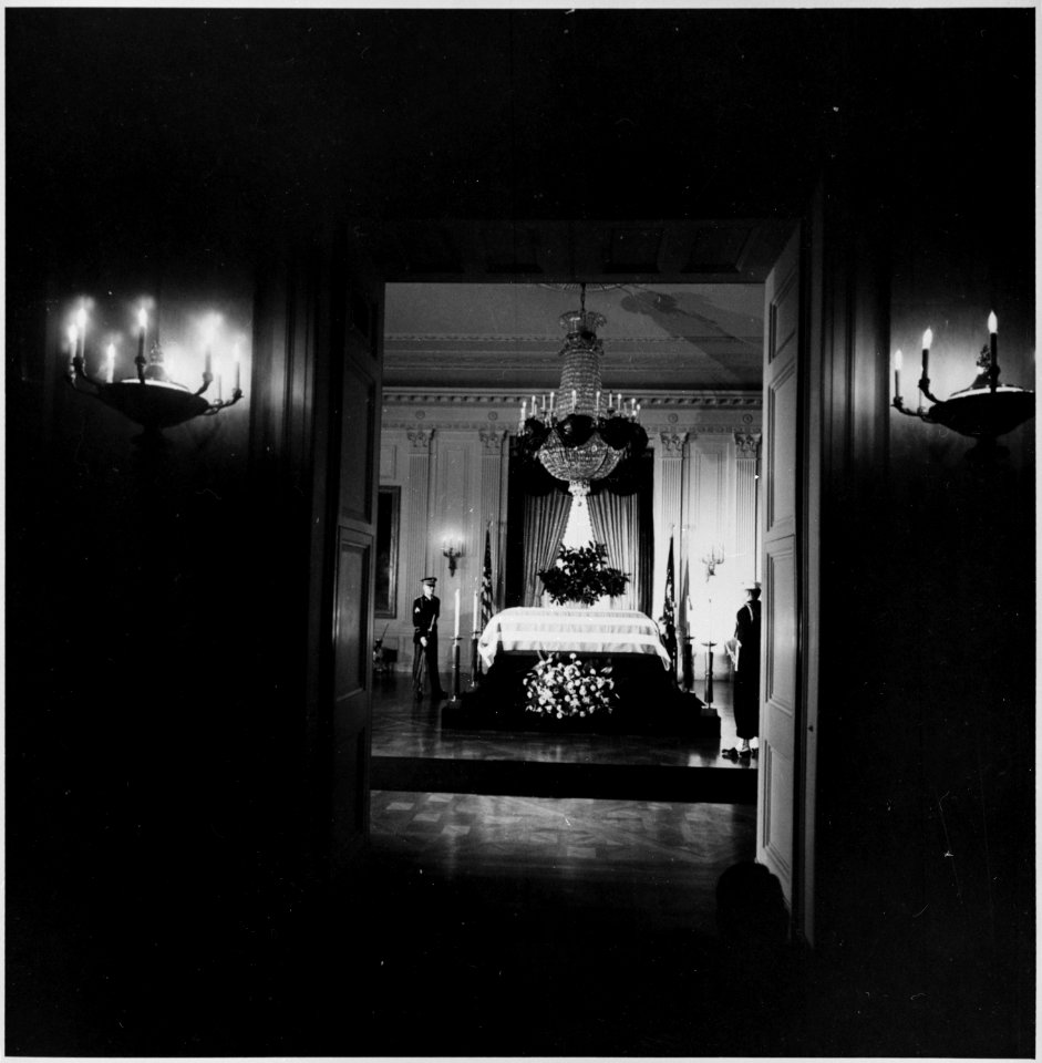Photograph of President Kennedy's flag-draped casket lying in state in the East Room of the White House. - NARA - 200448