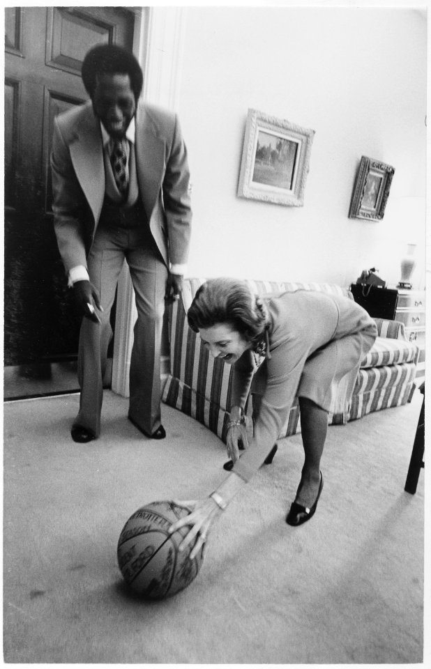 Photograph of First Lady Betty Ford Reaching to Pick up a Basketball Signed by the Harlem Globetrotters as Team... - NARA - 186785