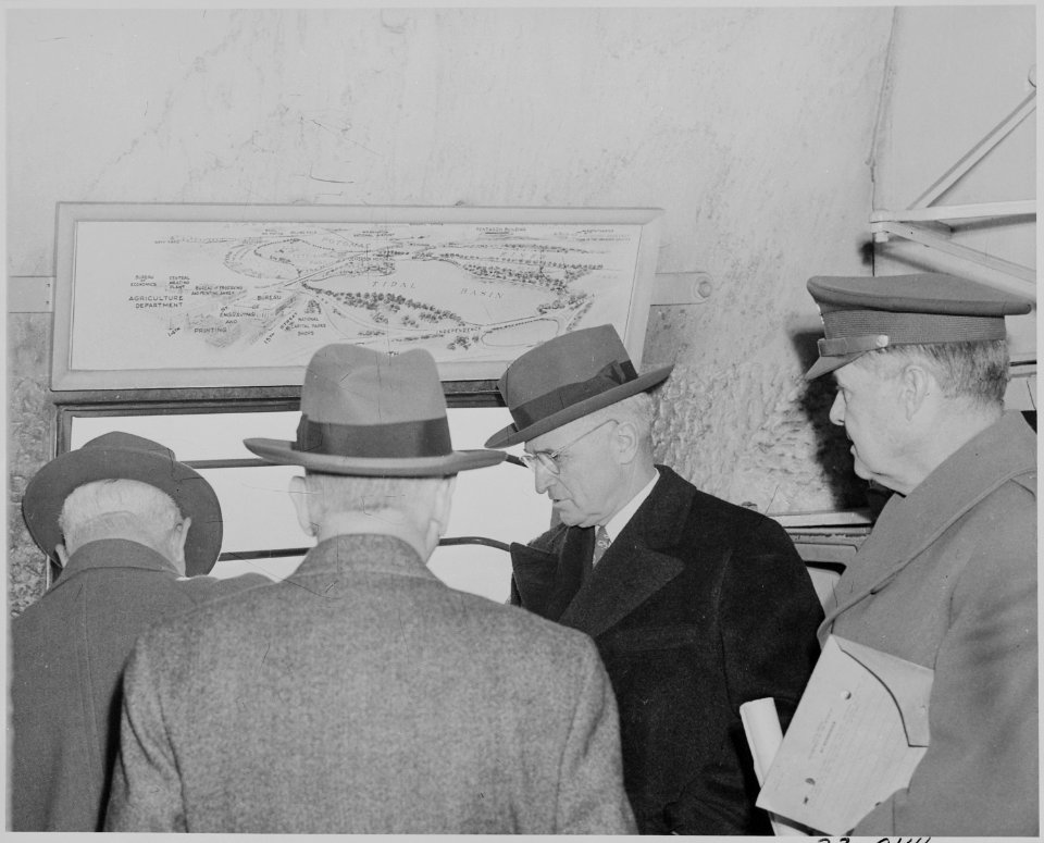 Photograph of President Truman and others around a window near the summit of the Washington Monument, looking out. - NARA - 199296